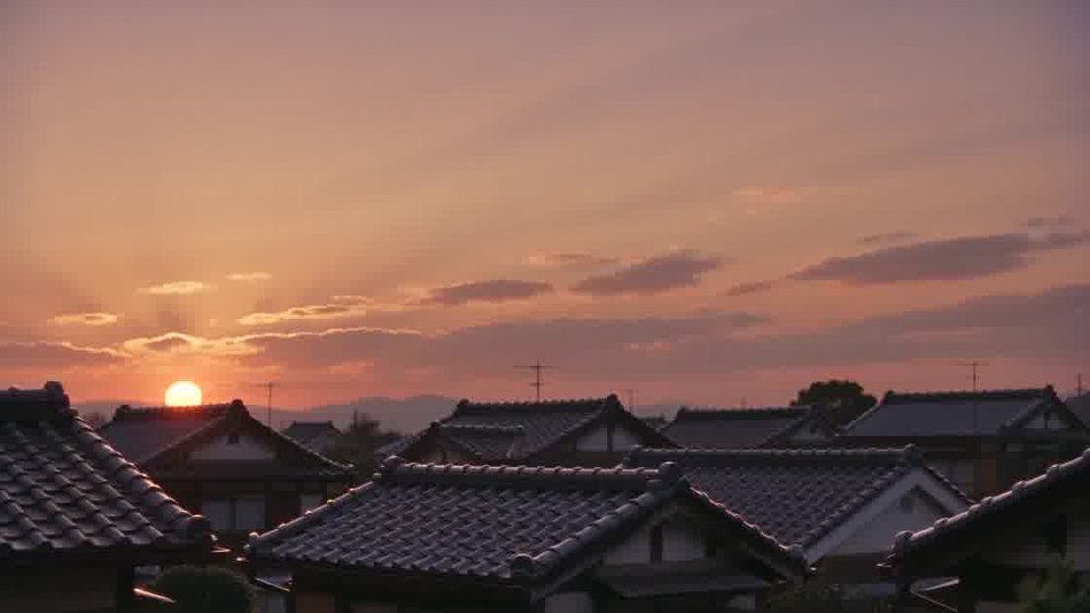 瓦屋根の向こうに沈む夕日