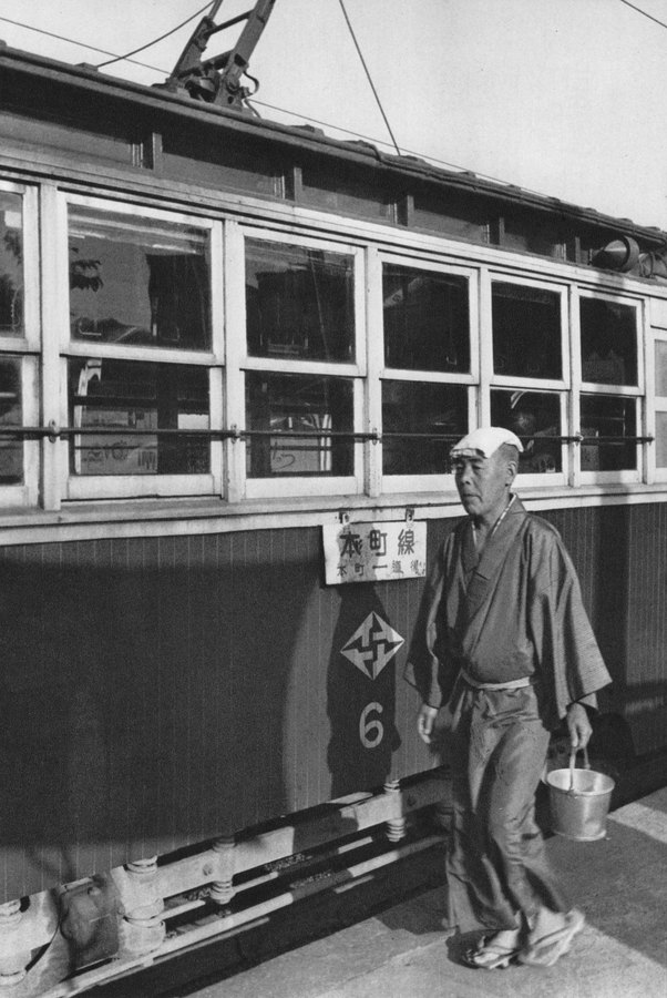 路面電車の前に立つ男性の白黒写真